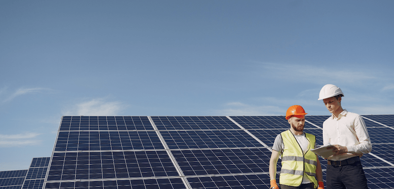 Two workers standing next to solar panels